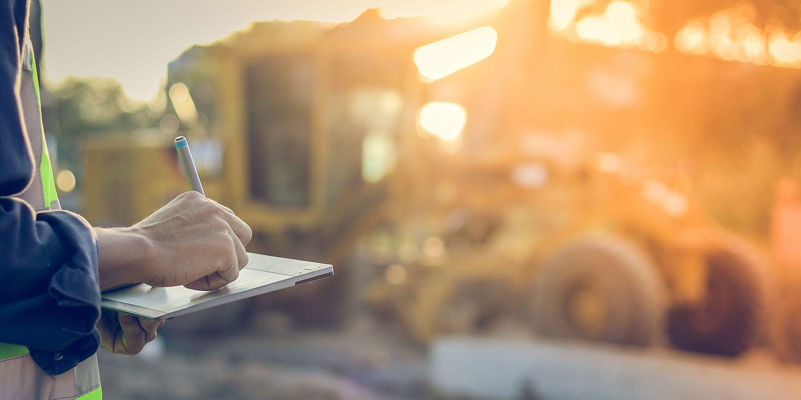 A person checks paperwork at a construction site.