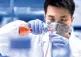 lab technologist pours liquid polymers into beaker